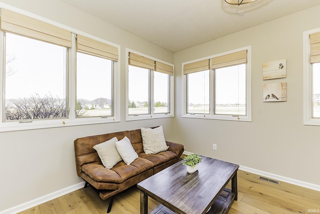 living area with visible vents, light wood-style floors, and baseboards