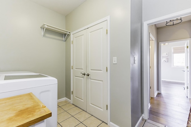 washroom featuring light tile patterned floors, washing machine and dryer, and baseboards