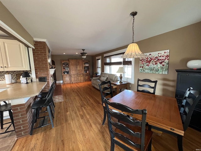 dining space with a fireplace, a ceiling fan, and light wood-style floors