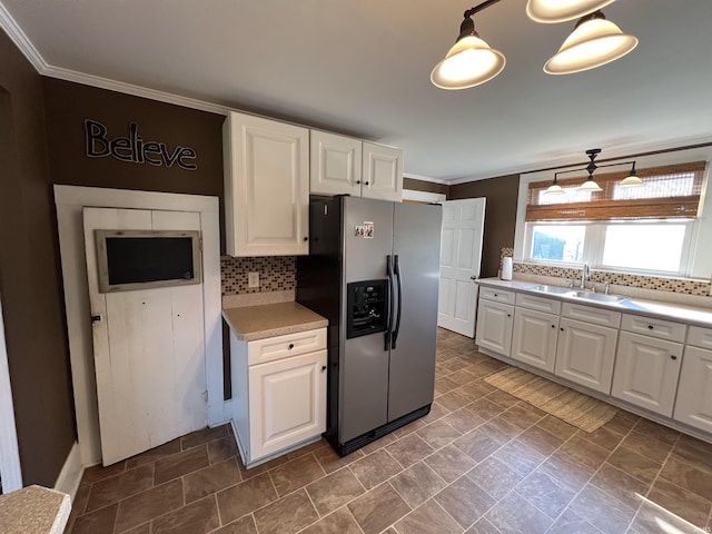 kitchen featuring a sink, tasteful backsplash, white cabinetry, stainless steel fridge, and light countertops