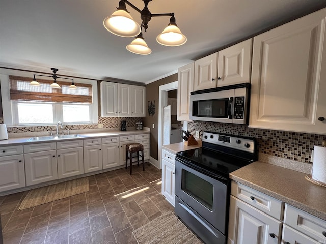 kitchen with tasteful backsplash, appliances with stainless steel finishes, white cabinetry, and a sink