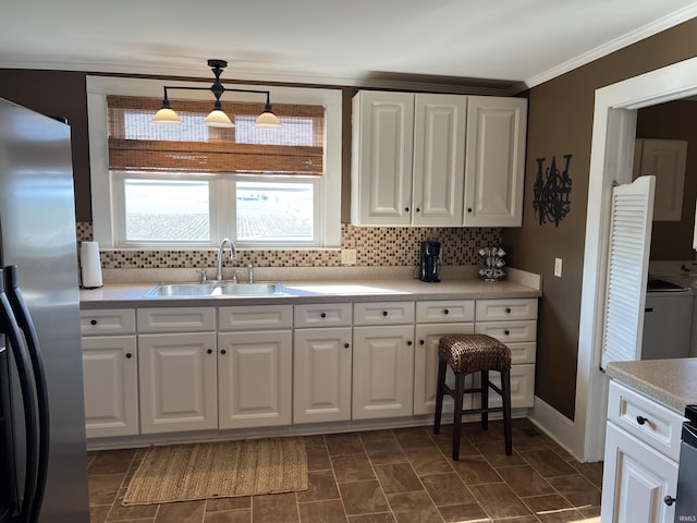 kitchen with white cabinets, freestanding refrigerator, and a sink