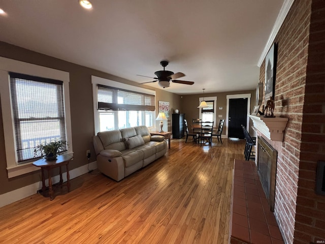 unfurnished living room featuring a ceiling fan, a healthy amount of sunlight, a fireplace, and light wood finished floors