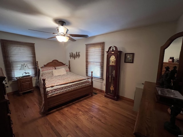 bedroom with a ceiling fan, wood finished floors, baseboards, and arched walkways