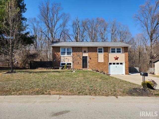 raised ranch featuring board and batten siding, concrete driveway, a garage, and a front yard