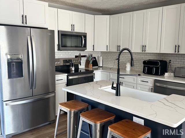 kitchen with white cabinets, wood finished floors, and stainless steel appliances