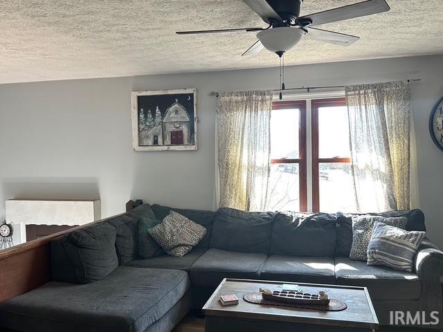 living room with a textured ceiling and ceiling fan