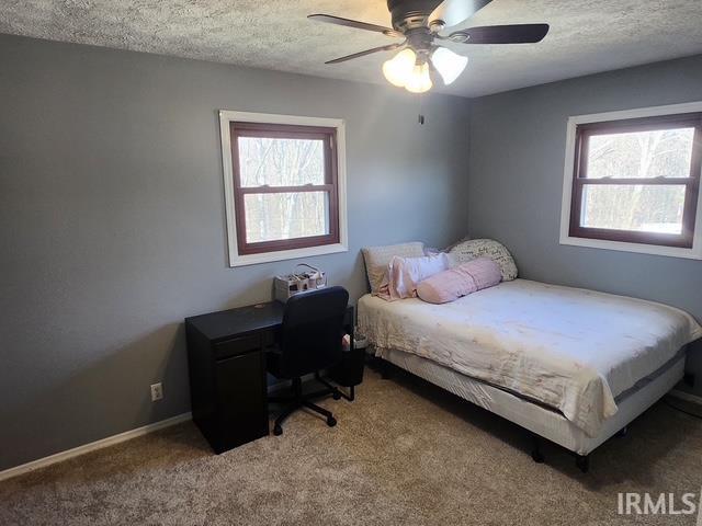 bedroom with ceiling fan, carpet, baseboards, and a textured ceiling