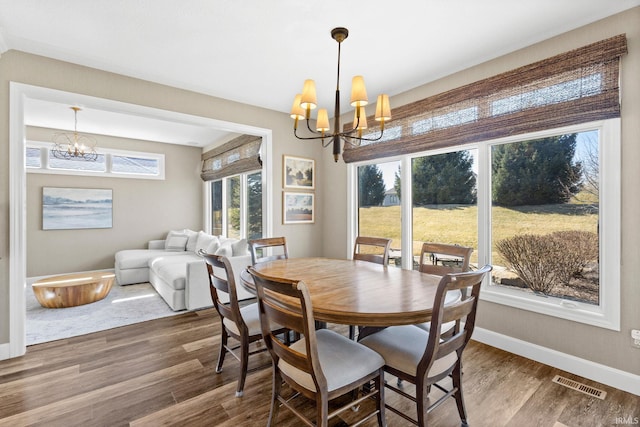 dining space featuring visible vents, baseboards, an inviting chandelier, and wood finished floors