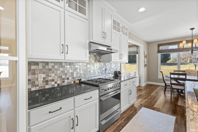 kitchen with dark wood-type flooring, under cabinet range hood, decorative backsplash, a notable chandelier, and stainless steel range