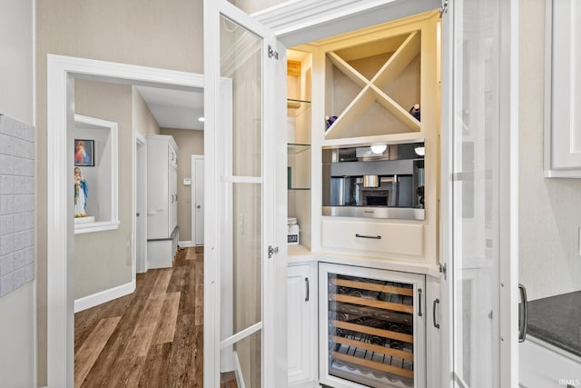 bar with wine cooler, wood finished floors, and baseboards