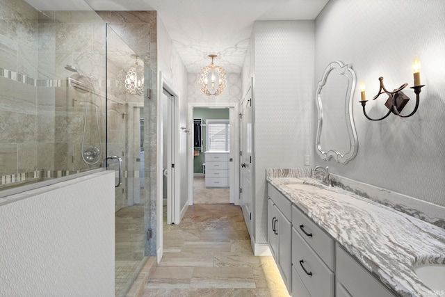 bathroom featuring an inviting chandelier, a stall shower, and vanity