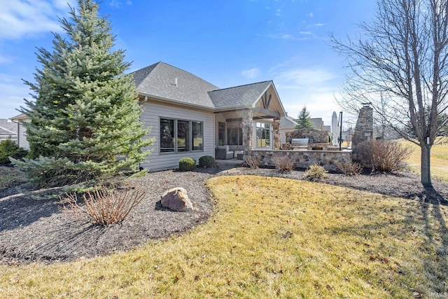 back of property with a yard, a patio, and roof with shingles