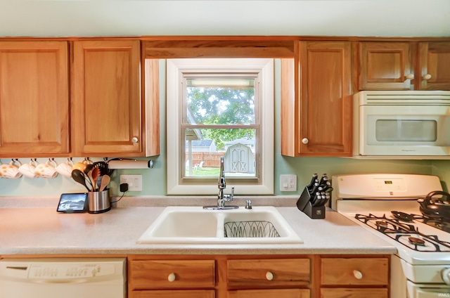 kitchen with a sink, white appliances, brown cabinets, and light countertops