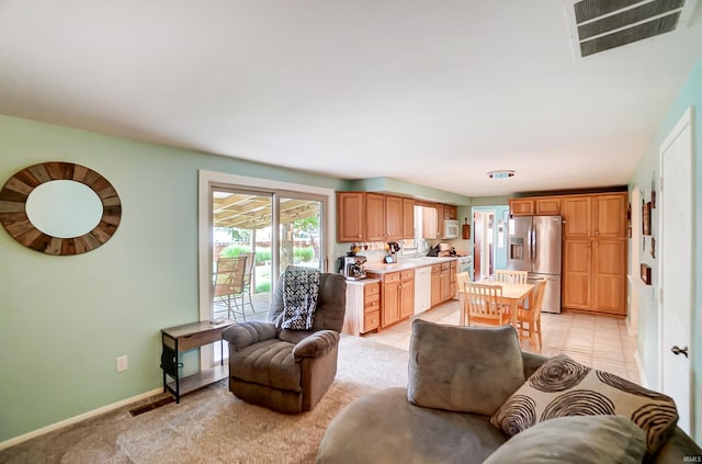 living area featuring visible vents, baseboards, light colored carpet, and light tile patterned flooring