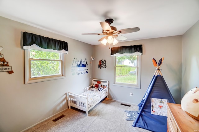 bedroom featuring visible vents, multiple windows, a ceiling fan, and carpet flooring