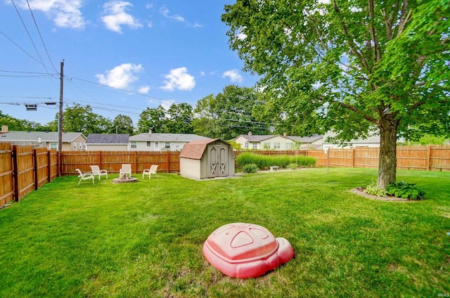 view of yard with a fenced backyard, a fire pit, a storage shed, and an outdoor structure