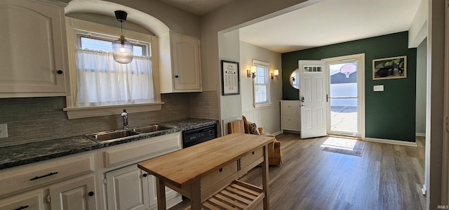 kitchen featuring a sink, decorative light fixtures, backsplash, wood finished floors, and baseboards