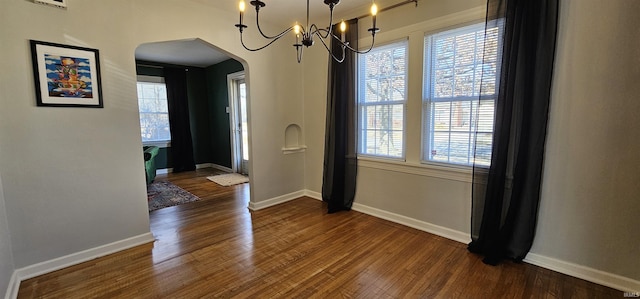 dining space featuring a wealth of natural light, baseboards, arched walkways, and dark wood-style flooring