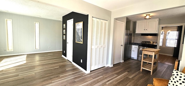 kitchen with electric stove, dark wood-style floors, white cabinets, baseboards, and extractor fan