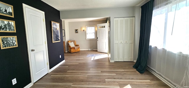 interior space featuring wood finished floors, baseboards, a closet, and a textured ceiling