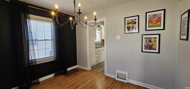 dining space with an inviting chandelier, wood finished floors, visible vents, and baseboards