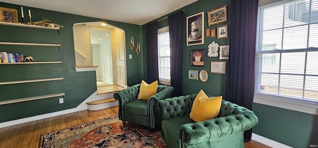 living area featuring stairway, wood finished floors, arched walkways, and baseboards