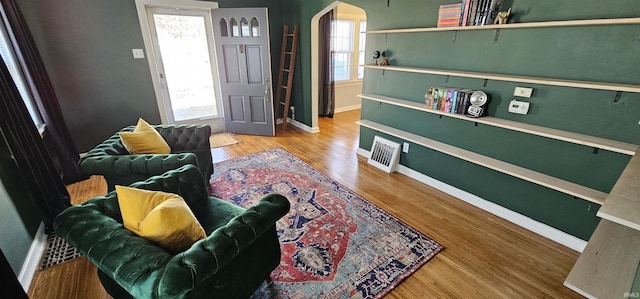 entryway with visible vents, wood finished floors, arched walkways, and baseboards