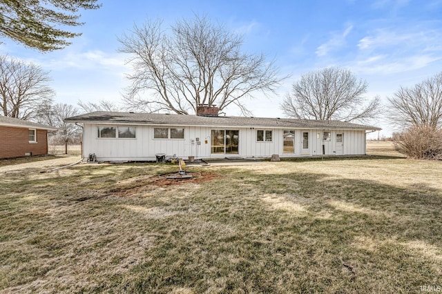 back of property with a lawn, board and batten siding, and a chimney