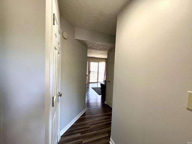 hall with baseboards, a textured ceiling, and dark wood-style flooring