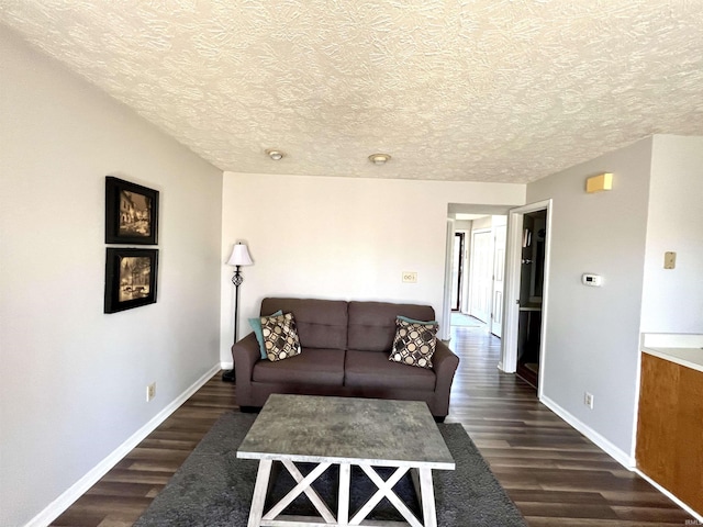 living area featuring baseboards, dark wood-type flooring, and a textured ceiling