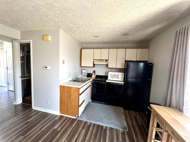 kitchen with black appliances, dark wood-type flooring, under cabinet range hood, light countertops, and a textured ceiling