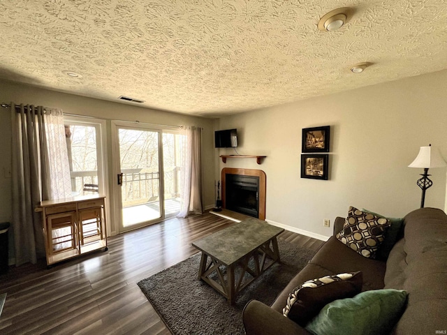 living area with dark wood finished floors, visible vents, a fireplace, and baseboards