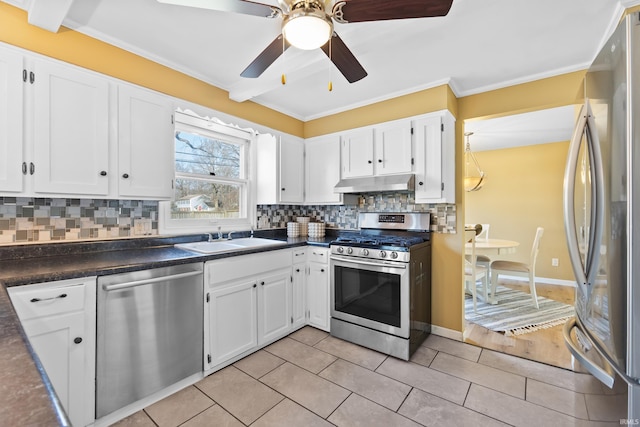 kitchen featuring under cabinet range hood, appliances with stainless steel finishes, dark countertops, and a sink