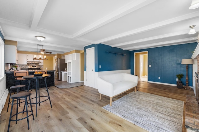 living room featuring beamed ceiling, light wood-style floors, and baseboards