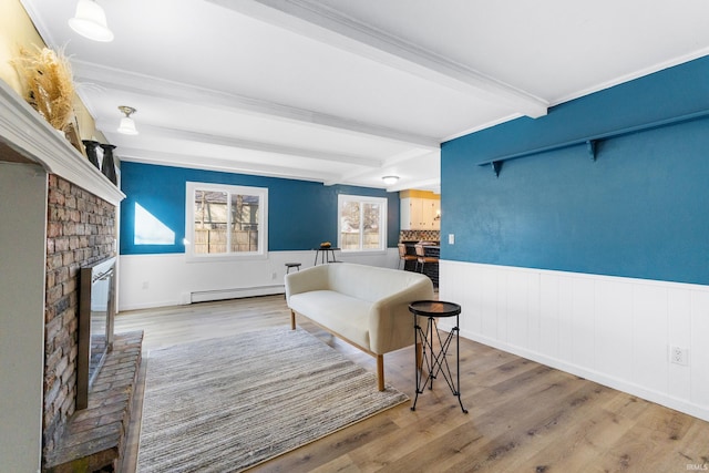 living area with wood finished floors, a fireplace, wainscoting, a baseboard heating unit, and beamed ceiling