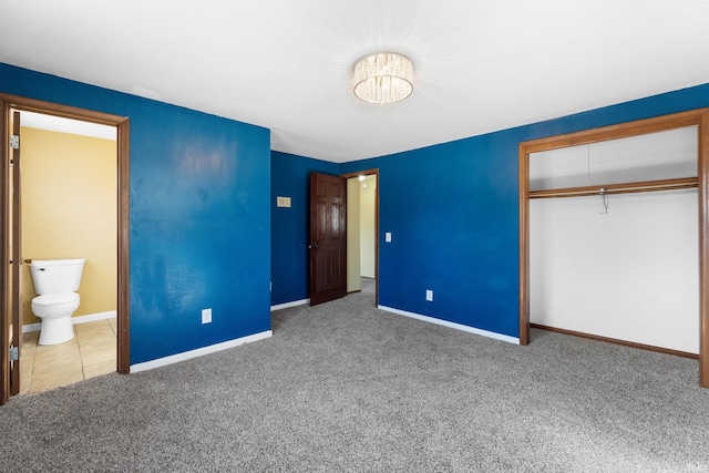 unfurnished bedroom with connected bathroom, carpet, a closet, and baseboards