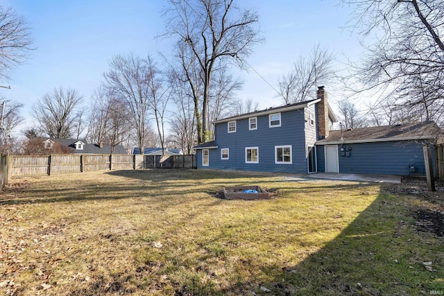 back of property featuring fence, a lawn, and a fire pit