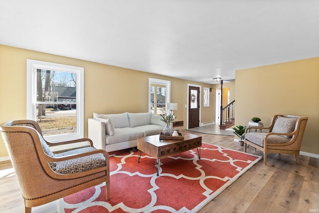 living room featuring a baseboard radiator, stairs, baseboards, and wood finished floors