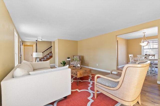 living room featuring baseboards, wood finished floors, and stairs