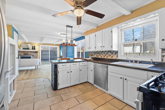 kitchen with dark countertops, open floor plan, appliances with stainless steel finishes, and a sink