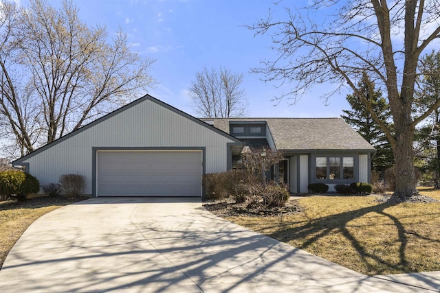 mid-century home featuring a garage, concrete driveway, and a shingled roof