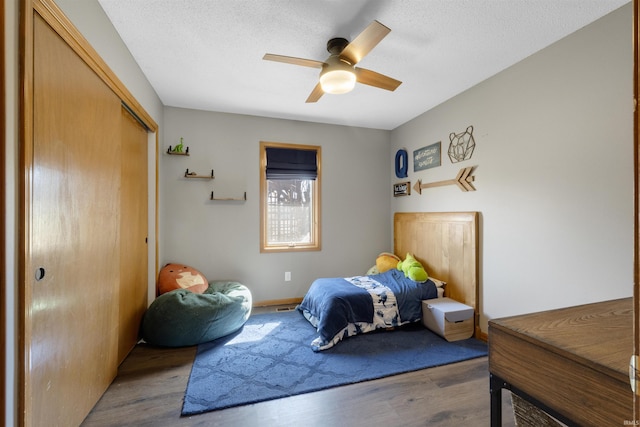 bedroom with a closet, a textured ceiling, wood finished floors, and a ceiling fan