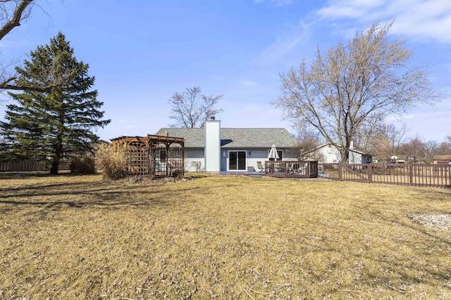 rear view of property featuring a wooden deck, a lawn, a pergola, and fence