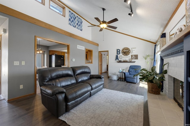 living area with a ceiling fan, wood finished floors, a fireplace, and visible vents