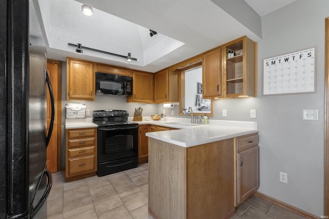 kitchen featuring black appliances, a sink, a textured ceiling, a peninsula, and light countertops