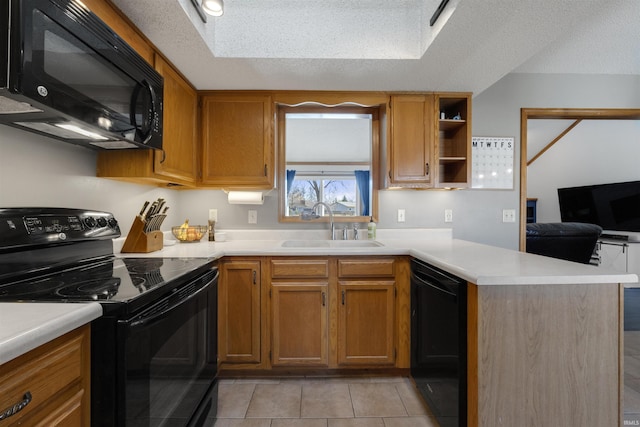 kitchen featuring black appliances, a sink, a textured ceiling, a peninsula, and light countertops