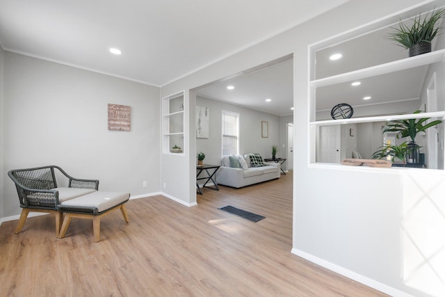 living area featuring visible vents, baseboards, ornamental molding, recessed lighting, and wood finished floors