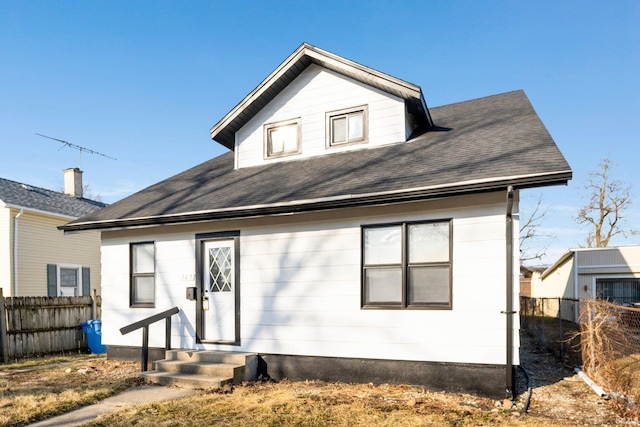 back of property featuring fence, roof with shingles, and entry steps