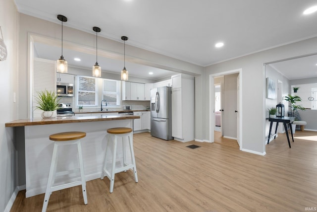 kitchen with visible vents, a kitchen bar, white cabinetry, appliances with stainless steel finishes, and a peninsula